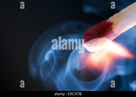 Macro photograph of a match at the exact moment of ignition, smoke swirls making interesting curlicue patterns Stock Photo