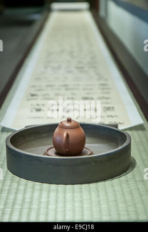 Brown teapot in front of long Buddhist scroll Stock Photo