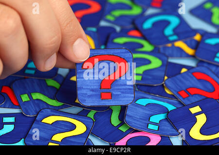 Woman's hand hold red question mark with background of question marks. Question Marks drawn by me. Stock Photo