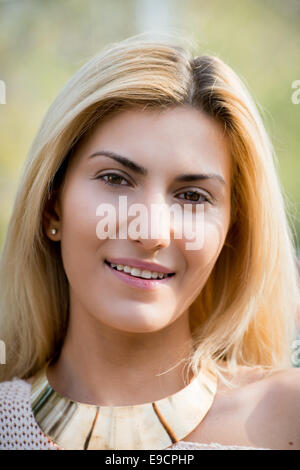 Close-up of blonde woman with golden necklace smiling Stock Photo