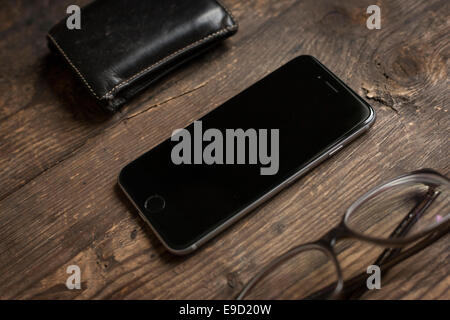 Wallet, glasses, and a smartphone on a wooden table. Overhead. Stock Photo