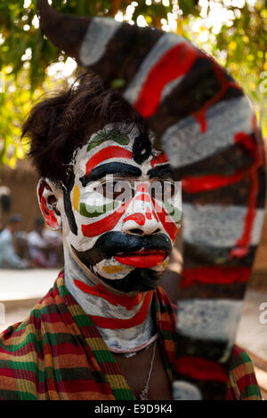 Young man holding sword with painted faces celebrating Gajan festival, Kolkata, West Bengal, India Stock Photo