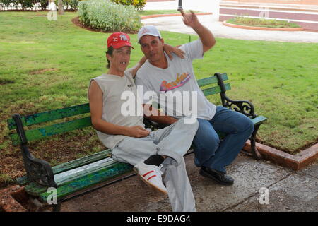 Two young Latin Cuban adult man sitting close friendly on the wooden bench in the park. Cuba Stock Photo