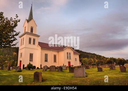 A white stave church in a Norway  village at sunset. Hdr image. Stock Photo