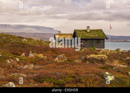 Cabin with turf roof near Hardangervidda National Park with Sloddfjorden lake in the background, Buskerud county, Norway Stock Photo