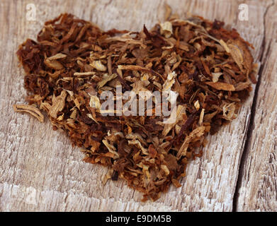 Dried tobacco leaves  decorated in heart shape on wooden surface Stock Photo