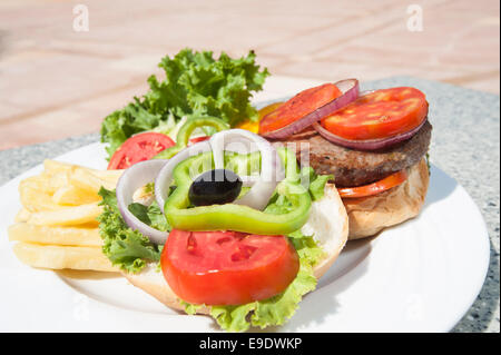 Closeup detail of a beef burger meal with bread bun and salad on plate Stock Photo