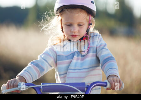 Small funny kid riding bike with training wheels. Stock Photo