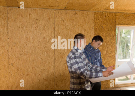 Middle Age Male Engineers Reviewing Building Interior Design on Blueprint at the Site. Stock Photo