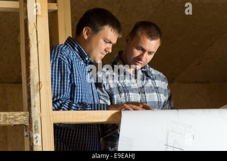 Two Middle Age Building Architects Reviewing Building Blueprint at the Site Seriously. Stock Photo