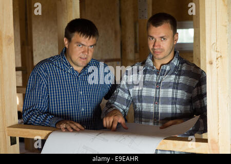Serious Middle Age Architect Men at Building Site with Blueprint Looking at Camera Stock Photo