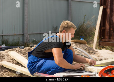 Workman on a building site taking a right angle measurement as he measure a wooden insulated beam before cutting and installing Stock Photo