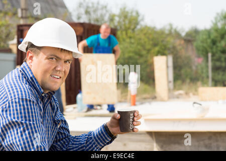 Male Engineer Holding Cup of Coffee While Looking at the Camera at Project Site. Stock Photo