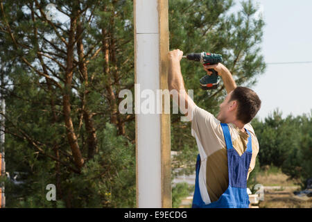 Solo Young Construction Man Using Cordless Drill Device in Building House Stock Photo