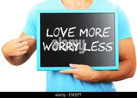 Man holding blackboard in hands and pointing the word LOVE MORE WORRY LESS Stock Photo