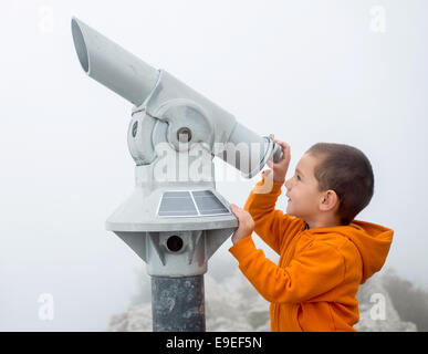 Boy looking into the sky through a monocular Stock Photo