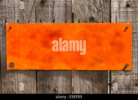 Textured  orange  rusty metal background, blank surface for your text. Screwed to rough wood panel fence