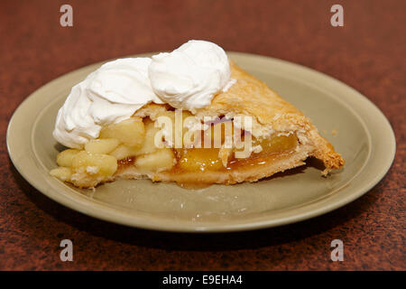 large slice of mass produced apple pie with whipped cream topping Stock Photo