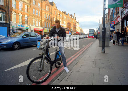 young man on Boris bike checking his mobile phone in Camden, London Stock Photo