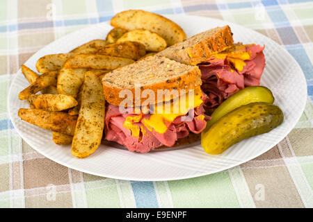 Corned Beef Sandwich Mustard Roasted Potatoes and Pickle on Plate Stock Photo
