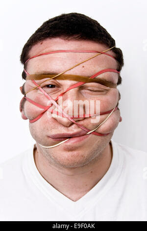 a man with rubber / elastic bands around his face squashing his nose and cheeks, Stock Photo