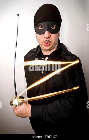 a man dressed in a funny mask of zorro outfit, with a sword, Stock Photo