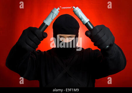 a man dressed in a ninja outfit with nunchucks Stock Photo