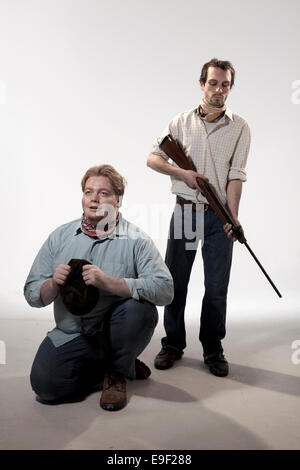 two men in the cowboy wild west era acting out scenes from of mice and men, dressed in period costume clothes one with a gun Stock Photo