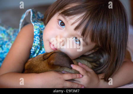 Toddler girl holding her puppy dog Stock Photo