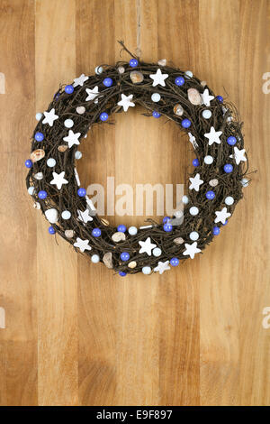 Decorated christmas door wreath with white stars and blue pearls brown twigs on sapele wood background, copy space Stock Photo