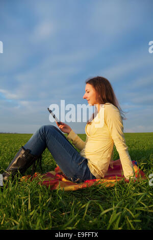 Teen girl reading electronic book outdoors Stock Photo