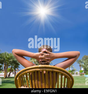 The girl sits in an armchair on a grass Stock Photo