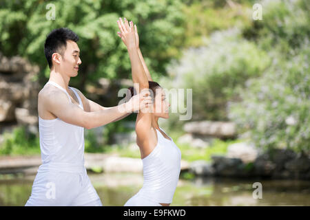 Yoga instructor helping woman with pose Stock Photo