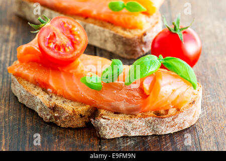 Two salmon sandwiches on wooden table Stock Photo