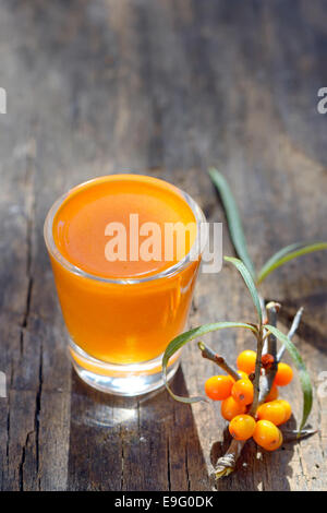 Sea buckthorn juice and berries isolated on wooden background. Natural detox. Stock Photo