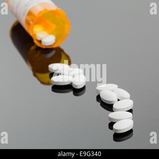 White tablets spilling from drug bottle Stock Photo