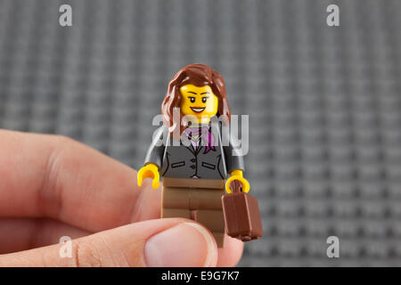 Tambov, Russian Federation - July 26, 2014 Lego businesswoman minifigure with brown suitcase in human hand. Stock Photo