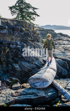 Boy walking on driftwood log, Ruckle Provincial Park, Salt spring Island, British Columbia, Canada Stock Photo