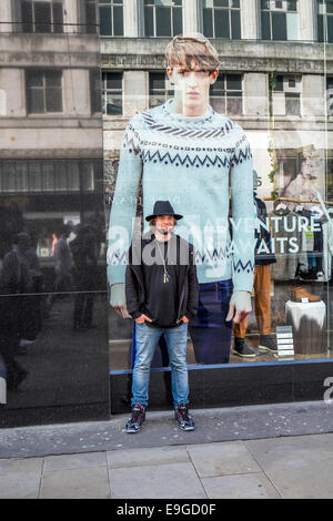 A man standing in front of a shop window with the image of a large model behind him Stock Photo