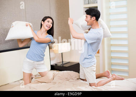 Young couple pillow fighting in bedroom Stock Photo