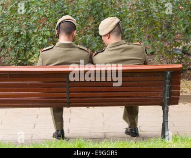Two Spanish armed forces personnel sitting on park bench. Spain, Europe Stock Photo