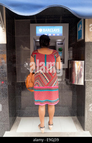 Mauritian woman using a Barclays bank ATM to get cash; Port Louis, Mauritius Stock Photo