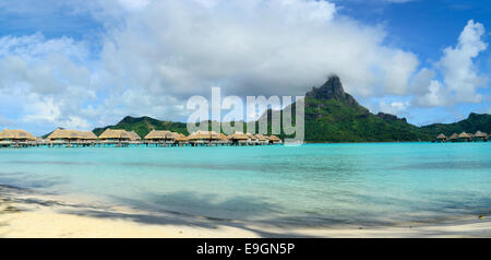 Panorama view on luxury overwater bungalows in a vacation resort in the clear blue lagoon of the tropical island of Bora Bora. Stock Photo
