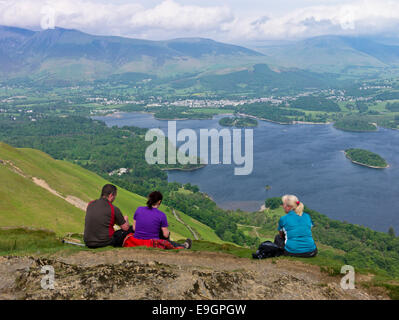 Three walkers resting and taking in the view of Derwent Water and the town of Keswick from Catbells Stock Photo