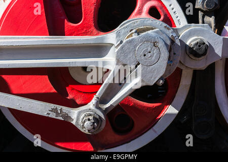 Closeup view of steam locomotive wheels, drives, rods, links and other mechanical details. White, black and red colors Stock Photo