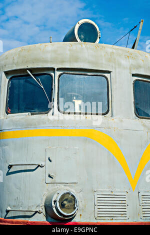 Closeup frontal view of an old diesel locomotive against the background of the blue sky and white clouds Stock Photo