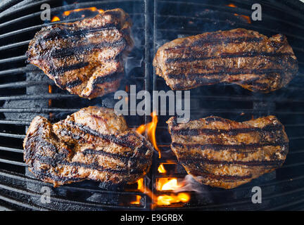 Steaks on the grill, being char grilled over flame. Stock Photo