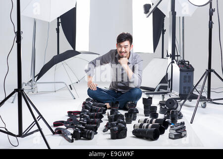 Photographer in studio with many cameras on the ground Stock Photo