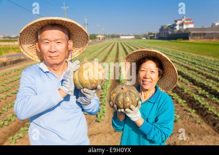 asian senior couple farmer holding pumpkin on his farm Stock Photo