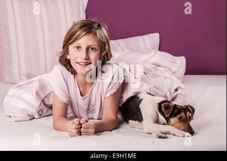 Girl lying in bed with a Danish Swedish Farmdog Stock Photo